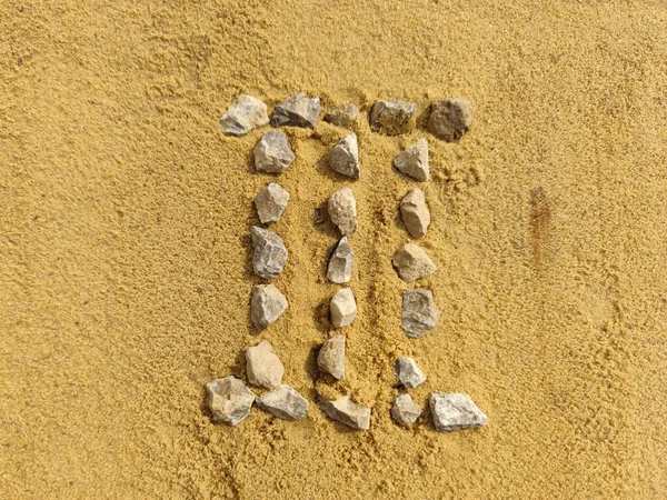 The Roman numeral 3 is laid out with stones on the river sand. — Stock Photo, Image