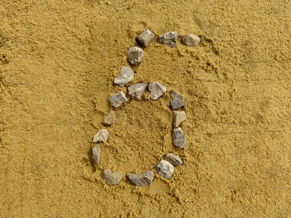 Numer 6 na piasku, złożone z drobnego żwiru — Zdjęcie stockowe