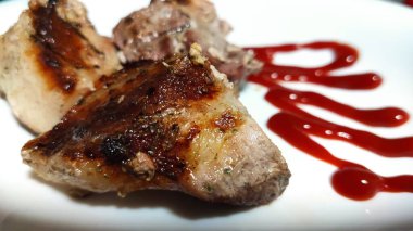 Beyaz bir tabakta kızarmış et parçaları ince ketçap çizgileriyle süslenir. Yüksek kalite fotoğraf