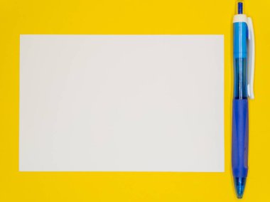 Sarı arka planda, beyaz bir kağıt ve mavi bir otomatik kalem, okula başlama konsepti. Uzayı kopyala Yüksek kalite fotoğraf