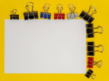 Sarı arka planda, beyaz bir kağıt ve ataç, okula başlama kavramı. Boşluğu kopyala. Yüksek kalite fotoğraf