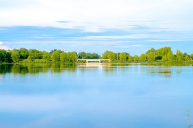 Peyzaj. Mavi gökyüzü ve su. Arkaplanda ağaçlar.