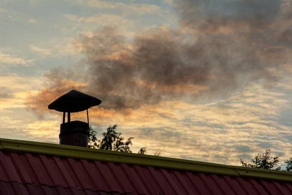 Duman evin bacasından geliyor, akşam gökyüzüne karşı..