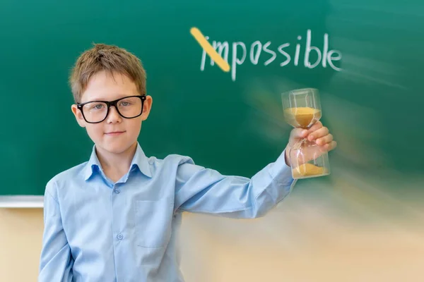 Een Schooljongen Houdt Een Zandloper Zijn Hand Achtergrond Een Schoolbord — Stockfoto