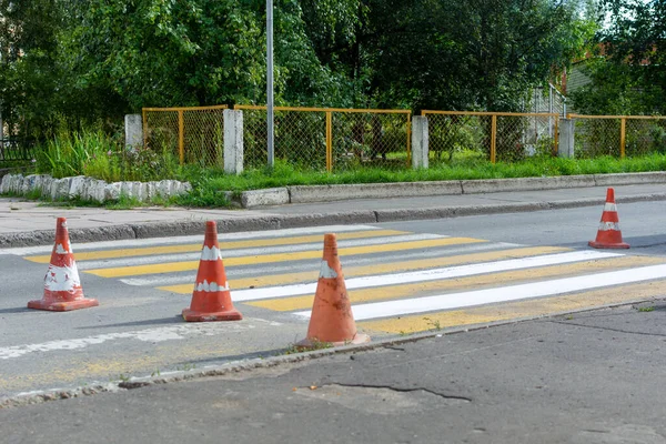 the repair of the road, orange cones around the pedestrian crossing.