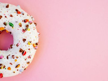 Beyaz kremalı yarım daire çörek ve pembe arka planda çikolata rengi gökkuşağı serpiştirilmiş. Lezzetli donut, en güzel manzara. Tatlı yemek aşıkları. Sağlıksız kalori yiyecekler.