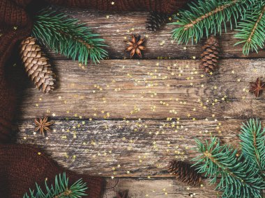 Yeni yıl için tatil kartı sıcak ve moda renklerde 2021 'dir. Noel kompozisyonu ladin dalları, koniler, anason, rahat süveter ve konfeti yıldızları kırsal ahşap arka planda. Düz yatış, üst görünüm