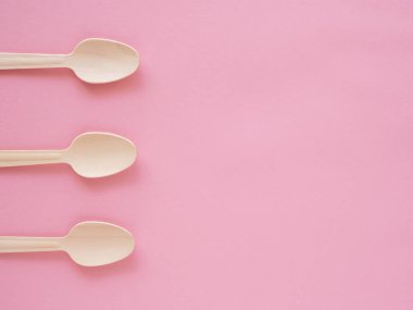 Çevre koruma ve koruma kavramı. Pembe kağıt arka planda tek kullanımlık mutfak gereçleri. Ekoloji, sıfır atık. Tahta, ayrıştırılabilir, üç kaşık. Minimalizm kavramı