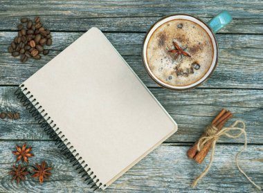 Baharatlı ikinci bardak kahve, kış ve sonbahar sıcak içeceği ahşap arka planda. Boş el işi defterinde bir fincan kahve, anason, tarçın ve kahve var. Düz yatıyordu. Sonbahar modeli