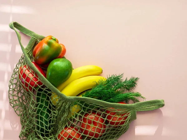 Zero waste food shopping. Eco friendly natural bag with fruits and vegetables. Sustainable lifestyle concept. Plastic free items. reuse, reduce, recycle, refuse. Groceries on pink background. Flat lay