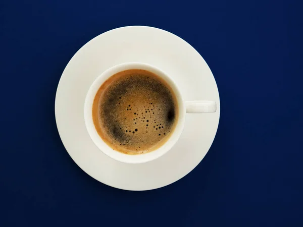 Una tazza di caffè nero su uno sfondo blu alla moda, vista dall'alto. Espresso o americano. Caffè e bar, concetto di arte barista. Minimalismo. — Foto Stock