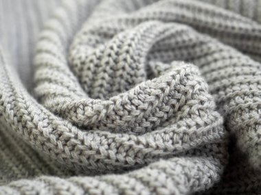 Ilık gri kazak ya da eşarp ördüm. Ev atmosferinde rahat bir kompozisyon. Yün kumaş dokusu arka planı kapatın. Rahat bir kumaş. Dalgalı kumaşı katlar. Yumuşak odak