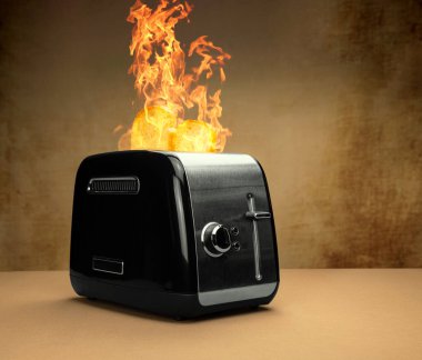 Yanan siyah gümüş tost makinesi, üzerinde büyük alevler, pişmiş hazır tost kahverengi yapılandırılmış arka plan tarafsız gümüş renkleri olan kahverengi bir masada.