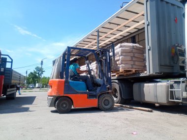 Krasnodar, Rusya - 13 Haziran 2019: Forklift kullanan bir kamyondan çimento torbaları indiriliyor.