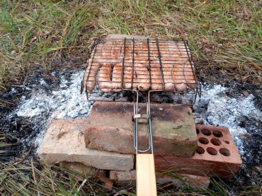 Izgaradaki banyolardan çıkan barbekü. Kızarmış sosisler ateşte.