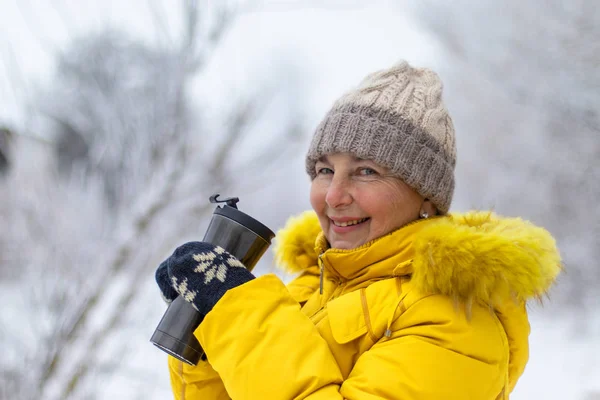 Femme adulte en veste d'hiver jaune dégustant du café un jour d'hiver . — Photo