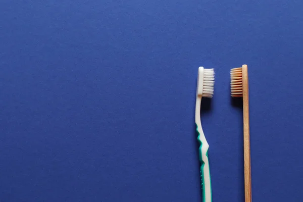 Cepillo de plástico dental y cepillo de madera sobre fondo azul — Foto de Stock