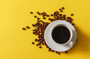 Sarı bir arka plan üzerinde dağınık fasulye ile kahve fincan sıcak