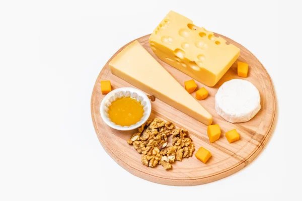 Různé sýry na desku kulaté dřevěné desky — Stock fotografie