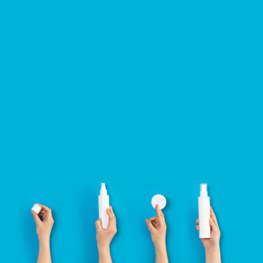 Mavi arka planda izole edilmiş Kozmetik Konteyner el tutma.