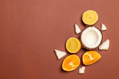 Taze egzotik meyveler: ananas, hindistan cevizi, portakal, kahverengi bir arka plan üzerinde limon.