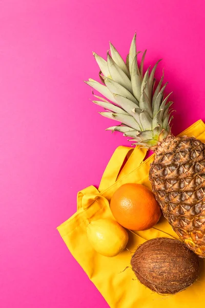 Frutas tropicales con una bolsa de algodón amarillo sobre un fondo rosa — Foto de Stock