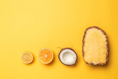 Bir pastel arka plan üzerinde Tropikal ananas, portakal, limon ve hindistan cevizi.