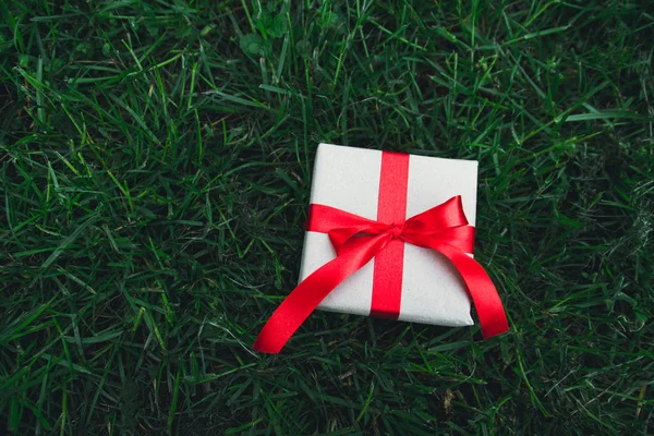 Presentförpackning på grönt gräs bakgrund med som present till jul, nyår, alla hjärtans dag eller årsdag. — Stockfoto