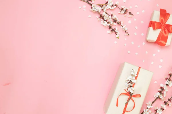 Composición de primavera. Caja de regalo de cumpleaños con ramitas de flores sobre un fondo rosa. Vista superior, cama plana. Diseño para una fiesta o invitación de cumpleaños . — Foto de Stock