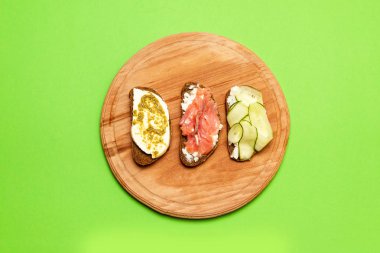 Farklı dolgular ile çeşitli sandviçler: bir leylak arka plan üzerinde balık, peynir ve salatalık ile.