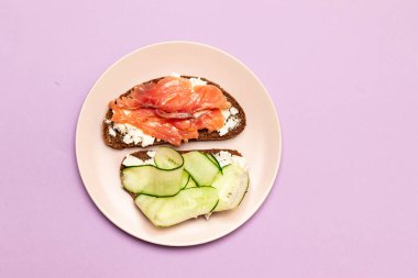 Arka planda peynir ve salatalık ile Balık sandviç.