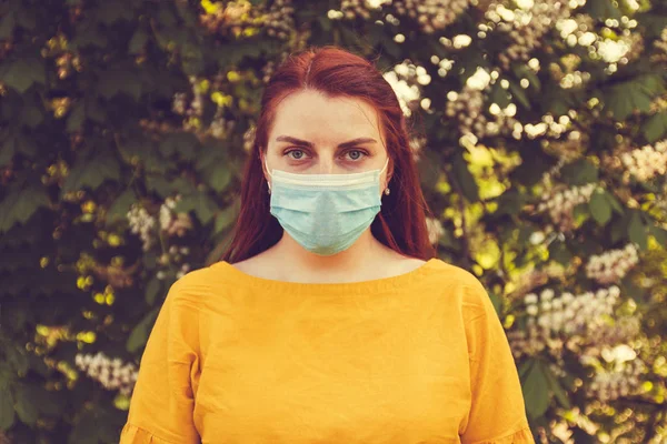 Bad ecology and dirty air. A woman with red hair and a mask to protect against infections and viruses on the street.