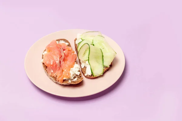 Morgon frukost med diverse smörgåsar och olika fyllningar: med fisk, ost och gurka på en lila bakgrund. — Stockfoto