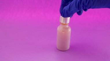 Vücut cilt bakımı için doğal kozmetik. Pembe arka planda pipetli cam şişe. Laboratuvarda kozmetik lerin test edilmesi ve üretimi.