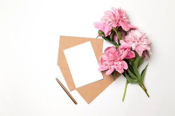Mockup amplop bisnis horisontal dengan selembar kertas putih dengan karangan bunga peoni indah dengan latar belakang abu-abu . — Stok Foto