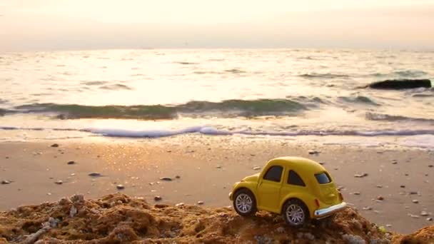 Φωτεινό Μικρό Ρετρό Παιχνίδι Αυτοκίνητο Στην Άμμο Στα Κύματα Φόντο — Αρχείο Βίντεο