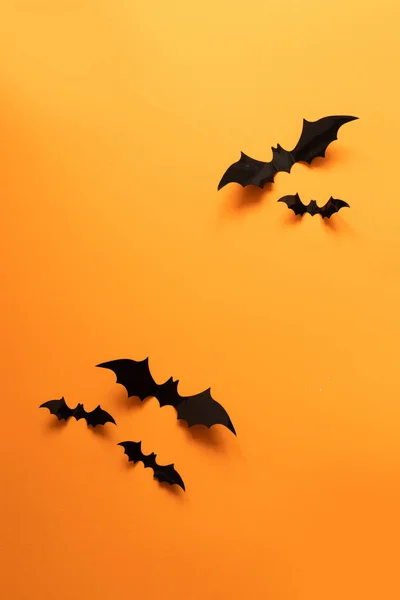 Creativa composición de Halloween vista superior de murciélagos de papel negro volar sobre un fondo naranja —  Fotos de Stock