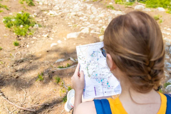 Aventura, conceito de viagem. Viajante turístico mulher loira senta-se em um log, olhando um mapa e escolhe a rota — Fotografia de Stock