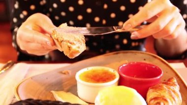 Dişi el elinde taze bir parça ekmek tutar ve pate ile lekeler. Bir kafede kahvaltı. Çeşitli yemek türleri ile masa