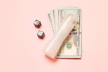 Dolar banknotları, pembe bir arka plan üzerinde zar ve yağlama ile. Para için seks.
