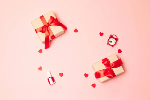 March 8, International Women's Day, Valentine's Day. Surprise gift boxes with a red ribbon bow, nail polish and a red clock on a pink background — Stock Photo, Image