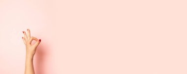 Pembe arka planda izole Ok jest gösteren genç kadın el yakın fotoğraf