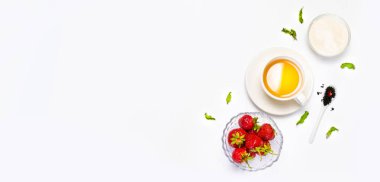 Beyaz fincan çay ve taze çilek, zencefil parçaları, portakal, nane ve şeker gri bir arka plan üzerinde. Düz döşeme, üst görünüm.