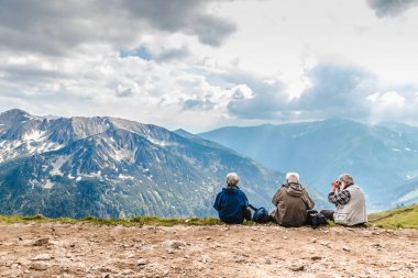 Polonya Tatras Polonya Haziran 3 2019: sırt çantaları ile yaşlı insanlar dağlarda yüksek yerde oturuyor. Yaşlı bir adam dürbünden bakar..