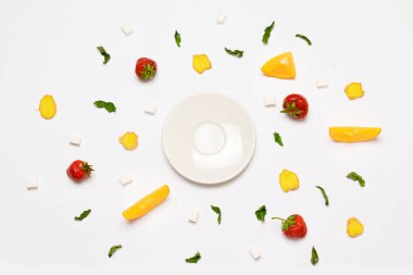 Kavram boş beyaz tabak, şeker küpleri, çilek, zencefil dilimleri, portakal ve nane yaprakları. Nesneler bir daire şeklinde düzenlenmiştir.