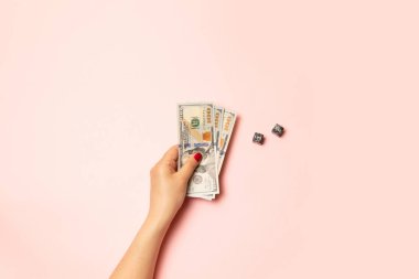 Strateji ve iş kavramı. Kırmızı manikür ile kadın el pembe bir arka plan üzerinde para dolar banknotları tutan. Soru işareti olan siyah küp.