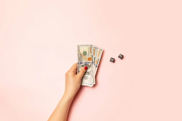 Strategy and business concept. Female hand with a red manicure holding money dollar bills on a pink background. Black cube with a question mark. — Stock Photo, Image