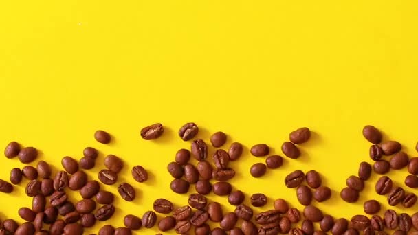 La mano femenina vierte granos marrones de café en una mesa amarilla de una bolsa de lona. Composición laica plana — Vídeos de Stock