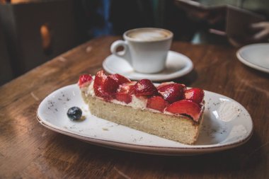 Yakın yukarı çilek pasta ile kahve latteon bir ahşap Vintage tablo
