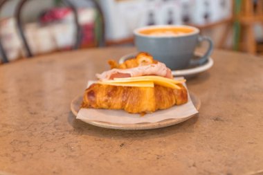 Taş masada kahve ve kruvasan sandviç. Fransız kahvaltısı.